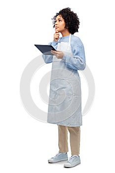 thinking woman in apron with tablet pc computer