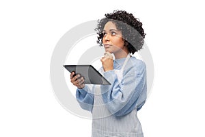 thinking woman in apron with tablet pc computer