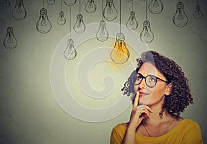 Thinking woman in glasses looking up with light idea bulb above head