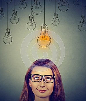 Thinking woman in glasses looking up with light idea bulb above head