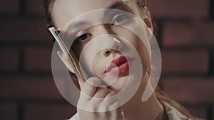 Thinking woman holding money stack near face and looking into camera