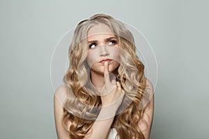 Thinking woman with long curly hairstyle on white background