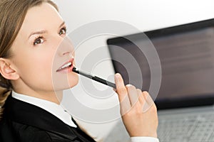 Thinking woman presenting laptop screen and pen