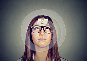 Thinking woman with sand clock sticker on forehead. Time management concept