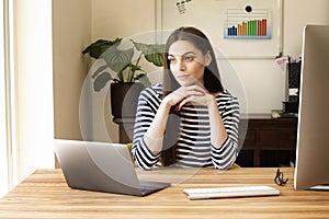 Thinking woman sitting and desk while working from home