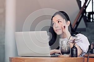 Thinking women with white laptop computer in co-working space