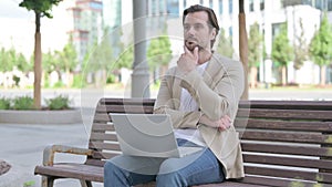 Thinking Young Man Using Laptop while Sitting on Bench