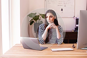 Thinking young woman using laptop and computer while working from home