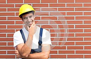 Thinking young worker in front of a brick wall photo