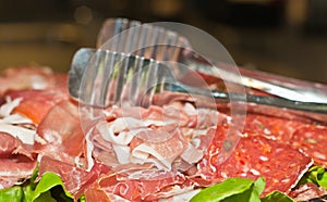 Thinly sliced brochette and salami on silver serving plate