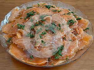 Thinly sliced cured salmon, gravlax, with dill on a glass plate ready for serving photo