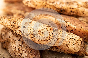 Thinly sliced homemade lard with pepper on white oiled paper, close-up, selective focus