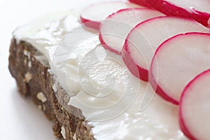 Thinly sliced radish on thickly spread cream cheese on dark bread photo