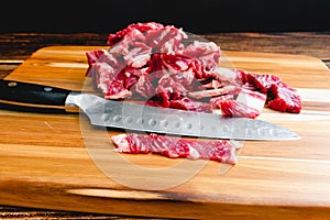 Thinly Sliced Ribeye Steak on a Wood Cutting Board with a Knife