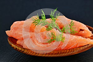 Thinly sliced smoked salmon fillet, on plate over black slate