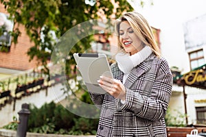 thinner adult businesswoman working on a tablet against the background of a city building