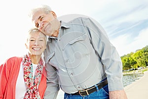 Thir love grows stronger each day. A loving senior couple standing together next to a lake.