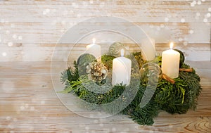 Third advent, natural advent wreath with white candles, three are lit, green Christmas glass baubles, pine cones and cinnamon,