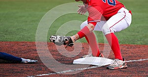 Third baseman ready to tag out the arm of a sliding runner during a baseball game photo
