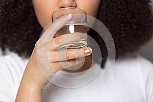 Thirsty African American girl drinking clean mineral water close up