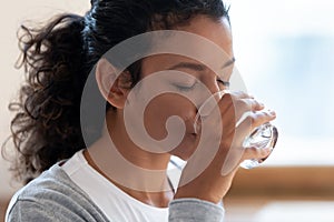 Thirsty african American woman drinking mineral water