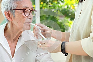 Thirsty asian senior woman drinking water with a straw,Do not use a straw to drink water prevent swallowing air causing flatulence photo