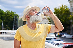 Thirsty bearded man drinking water on hot day