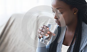 Thirsty black girl drinking clean water from glass at home