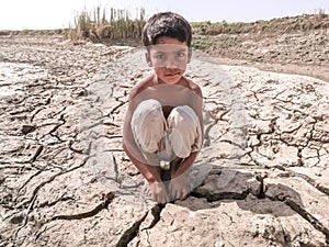 Thirsty child is sitting on dried land