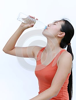 Thirsty fitness girl drinking bottle of water