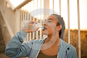Thirsty girl drinking from a water bottle after exercising.