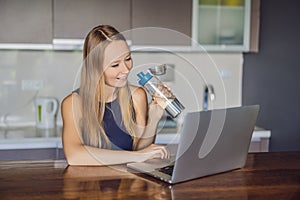 Thirsty girl drinks water, uses laptop computer for blogging in networks, watches film, connected to wireless internet
