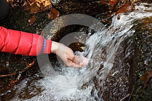 Thirsty hiker drinking water from a crystal clear spring