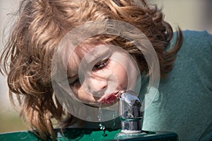 Thirsty kids. Close up head shot of child drinking water outdoor in park. Kids face, little boy portrait.