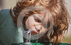Thirsty kids. Close up head shot of child drinking water outdoor in park. Kids face, little boy portrait.