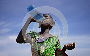 Thirsty Little African Girl Savoring Fresh Drinking Water From A Plastic Bottle