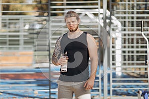 Thirsty man drinking sports cocktail from bottle during bodybuilding training. Tired athlete man drinking water from