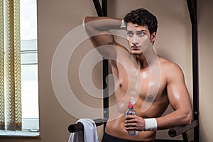 The thirsty man drinking water in sports gym