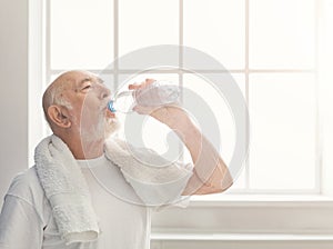 Thirsty senior man drinking water from bottle