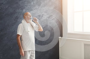 Thirsty senior man drinking water from bottle