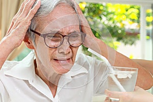 Thirsty senior woman with a brain freeze after drinking cold water with ice,Asian old elderly touching her head with hands,pain in