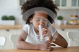 Thirsty small curly african american little child girl drinking water.