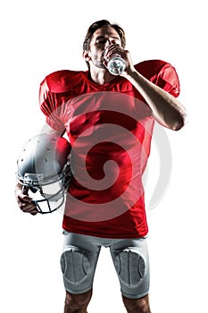 Thirsty sportsman in red jersey holding helmet while drinking water