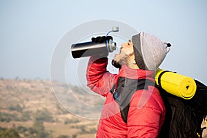 Thirsty travler drinking water by taking break while climbing - Concept of drink water before feeling thirsty photo