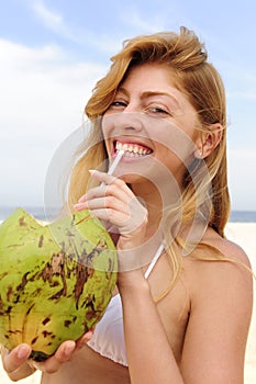 Thirsty woman drinking coconut water on the beach