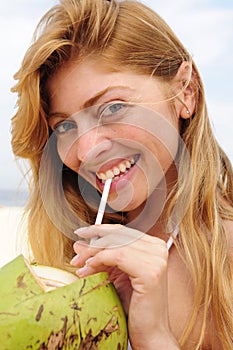 Thirsty woman drinking coconut water on the beach