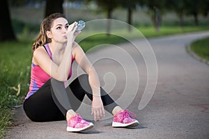 Thirsty woman drinking water to recuperate after jogging