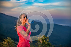 Thirsty woman trail runner drinking water from water bottle.