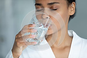 Thirsty young african american woman drinking glass of water.