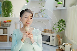 Thirsty young woman drinking milk from a glass in the kitchen